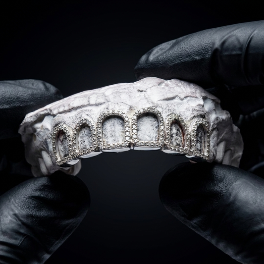 925 sterling silver custom 6-top open window grillz lined with pavé diamonds held on a plaster tooth cast by gloved hands.