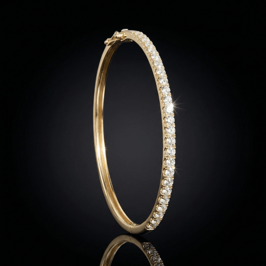 Yellow gold bangel braclet featuring pave set diamonds. The bangel stands upright on a mirrored surface.