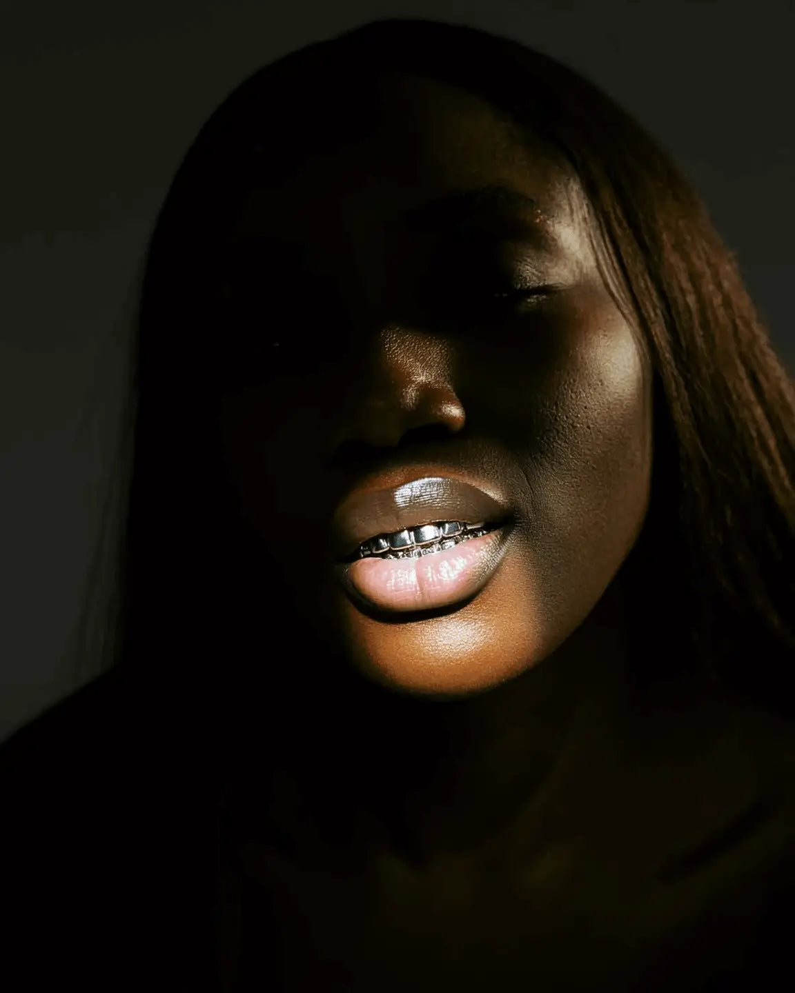 Photoshoot of a dark skinned model wearing silver grillz.