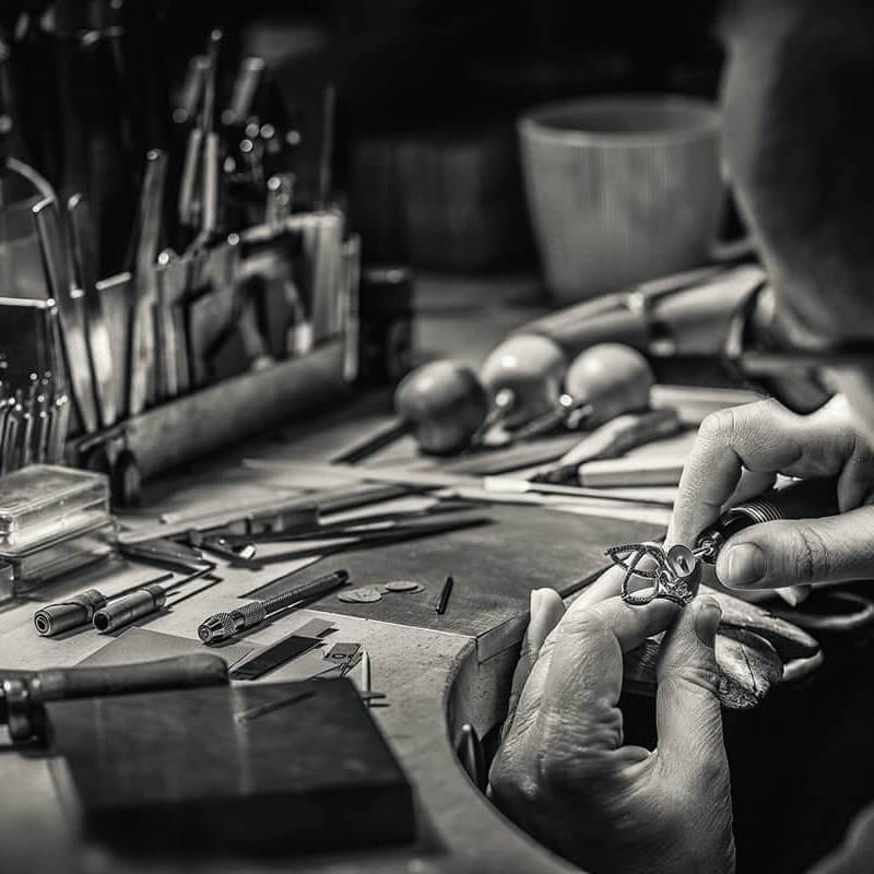 A goldsmith working on a ring. With tools scattered aroud his workbench.