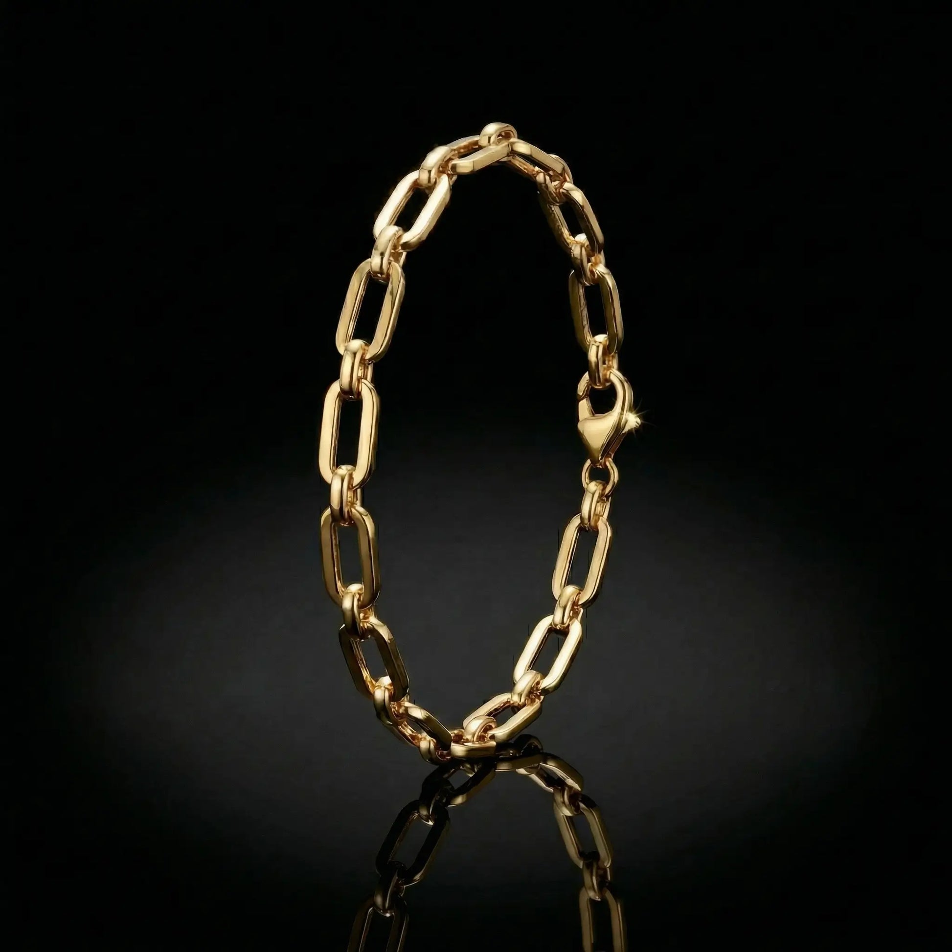 yellow golden womens paperclip bracelet laying on a mirrored surface.