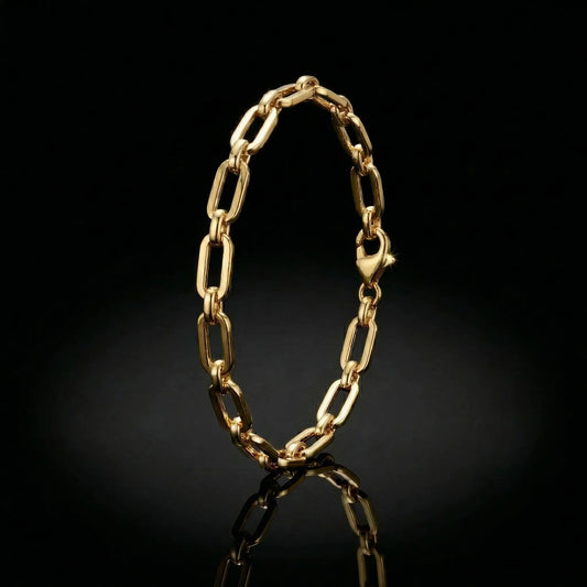 yellow golden womens paperclip bracelet laying on a mirrored surface.