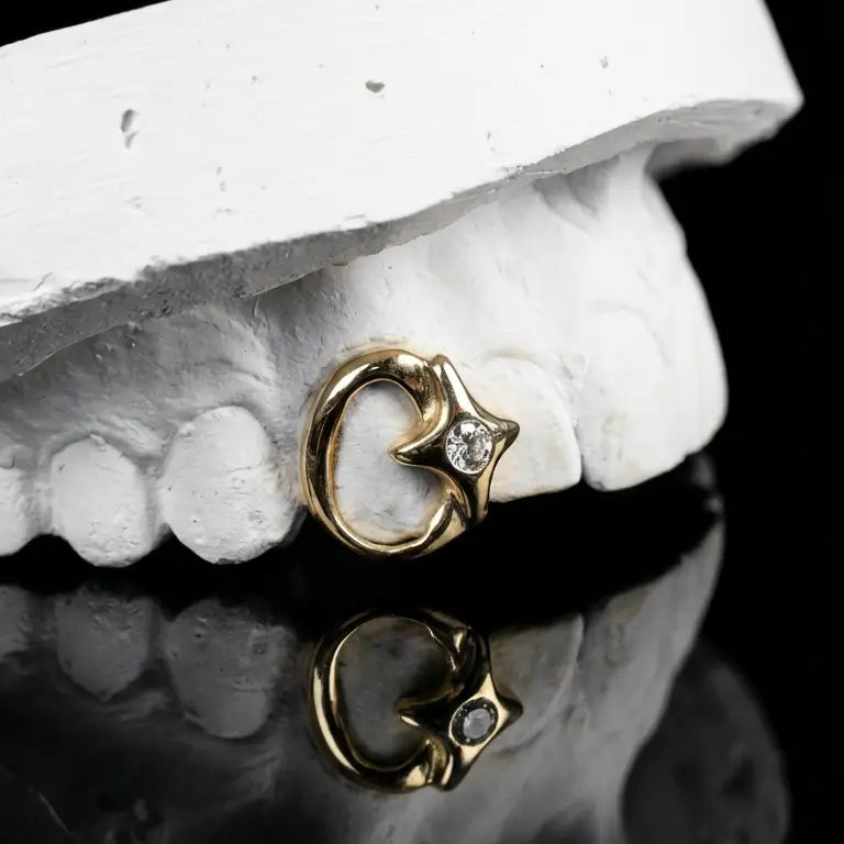 A golden grillz with an open design and a star which features a diamond.
